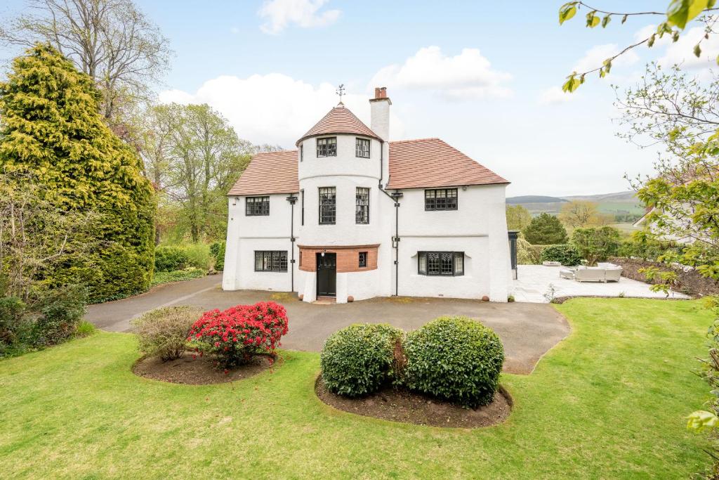 una gran casa blanca con arbustos en el patio en Unique Arts & Crafts Home in Auchterarder, en Auchterarder