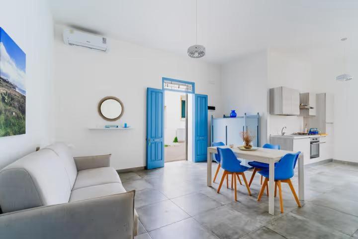 a living room with a table and blue chairs at Petracca home in Torre San Giovanni Ugento