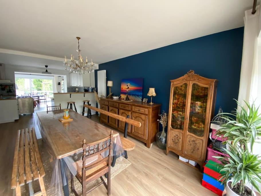 un salon avec une table et un mur bleu dans l'établissement Villa Mirabelle - Proche plage, à Merville-Franceville-Plage