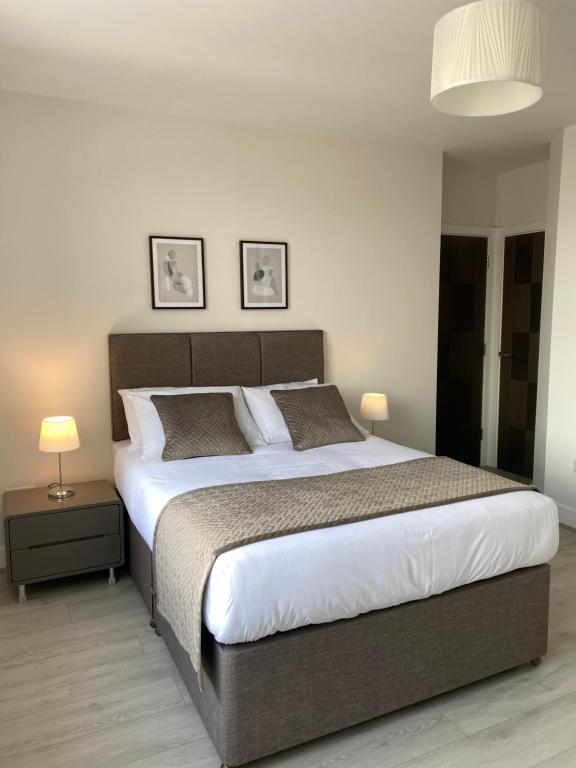 a bedroom with a large bed and two lamps at Dream Yard Apartments Westcliff in Southend-on-Sea