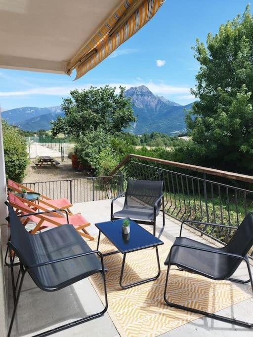 d'une terrasse avec des chaises, une table et des montagnes. dans l'établissement T3, 6 couchages 60m2 piscine, tennis vue sur lac, à Prunières