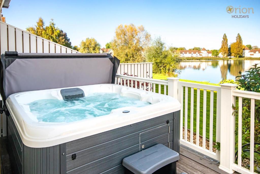 a hot tub on a deck with a view of a lake at Windrush Lake 20, Summit Lodge P in South Cerney
