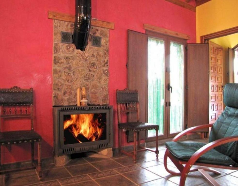 een woonkamer met een open haard en een rode muur bij Las Frascuelas in Almajano
