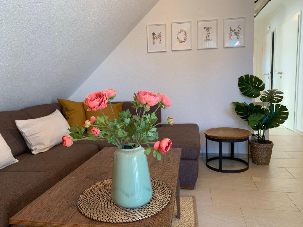 a living room with a vase with pink flowers on a table at Haus-am-See-Kolkstr-1-OG-rechts in Norddeich