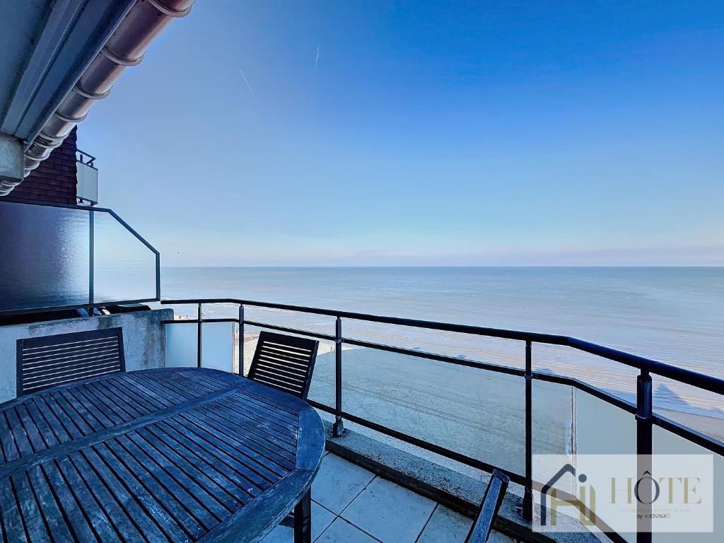 un balcon avec une table et des chaises et l'océan dans l'établissement Le Panoramique Marin- 2Ch, à Bray-Dunes