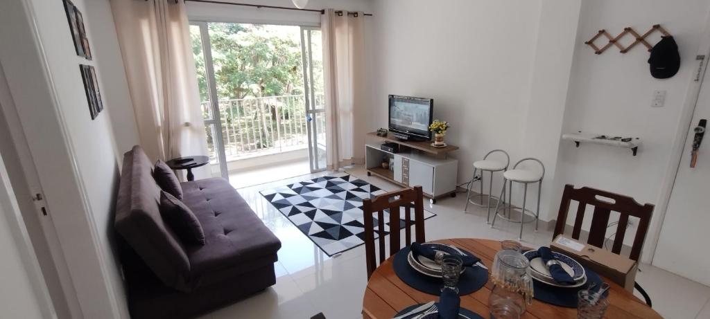 a living room with a couch and a dining room table at Apartamento Pé na Areia - Caraguatatuba in Caraguatatuba