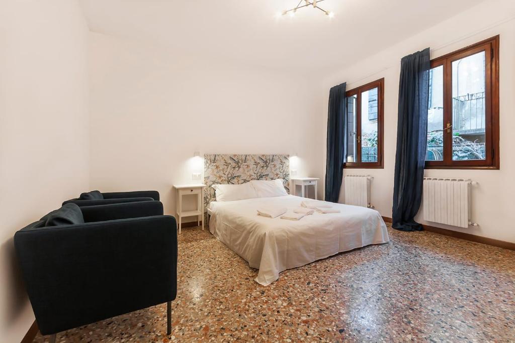 a bedroom with a bed and a chair and windows at Casa Alimante in Venice