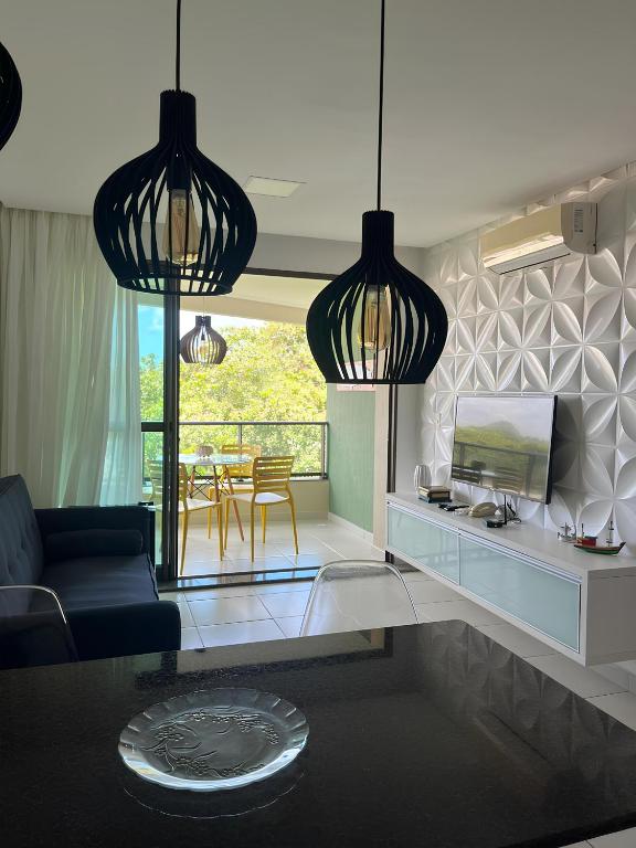 a living room with two pendant lights and a television at Apto 304-D, 1 quarto completo! in Tamandaré