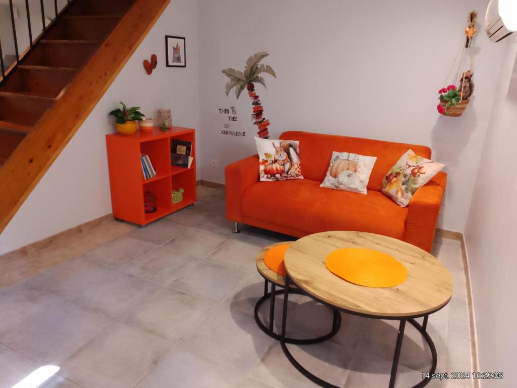 ein Wohnzimmer mit einem orangenen Sofa und einem Tisch in der Unterkunft charmante maisonnette au calme in Montélimar