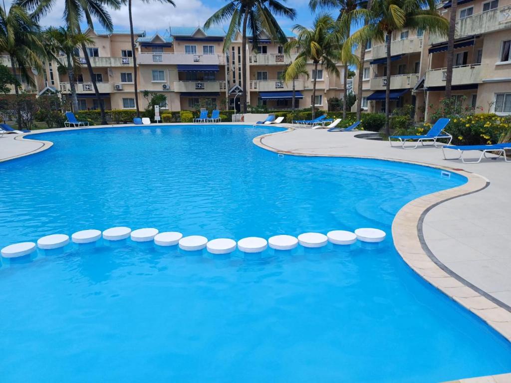 a swimming pool at a resort with chairs and palm trees at Le Dattier in Flic-en-Flac