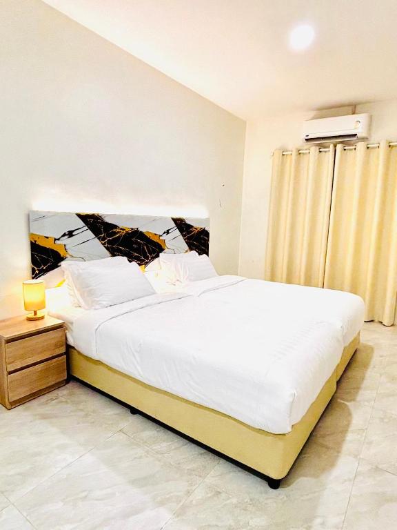 a bedroom with a large bed with white sheets at PJ Hostel & Bar in Pattaya