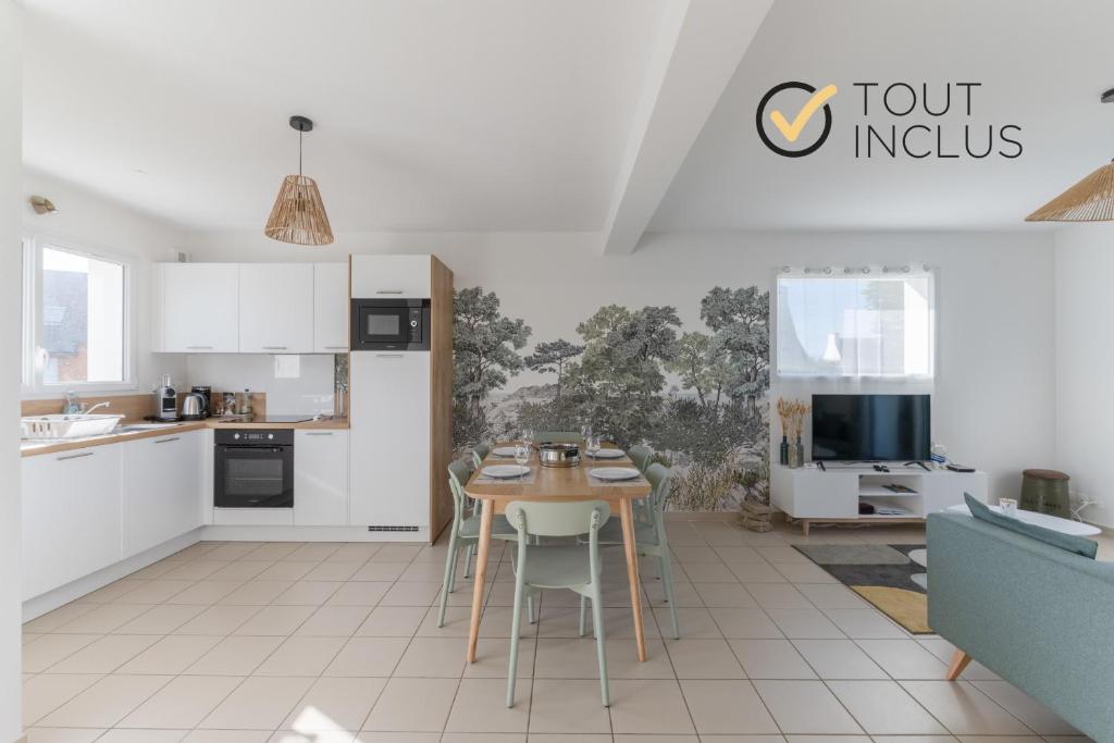 a kitchen with white cabinets and a table with chairs at AN 19 - Charmante maison a 300m de la mer in Porspoder