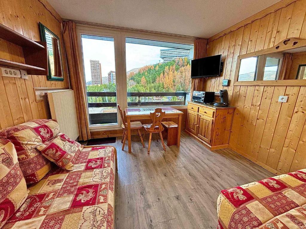 Cette chambre comprend un lit, une table et une cuisine. dans l'établissement Studio cosy pour 2 à La Croisette, ski aux pieds, parfait pour couples - FR-1-452-115, aux Menuires