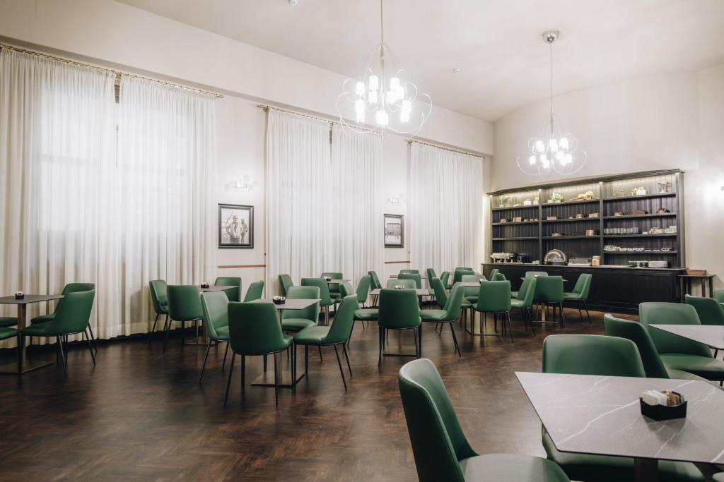 a dining room with green chairs and tables at Hotel Impero in Cremona