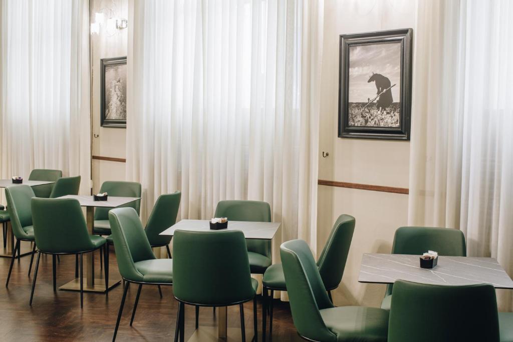 a dining room with tables and green chairs at Hotel Impero in Cremona