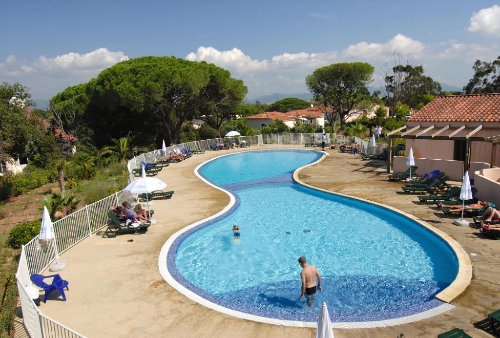 una piscina en un complejo con un hombre de pie en él en Résidence Odalys Domaine des Eucalyptus, en Saint-Aygulf