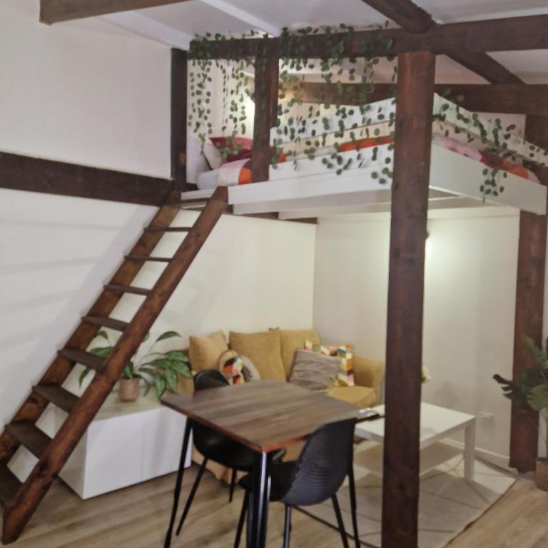 Cette chambre comprend une mezzanine, une table et des chaises. dans l'établissement Paris Villette by metro 7, France Stadium, break moment studio, à Aubervilliers