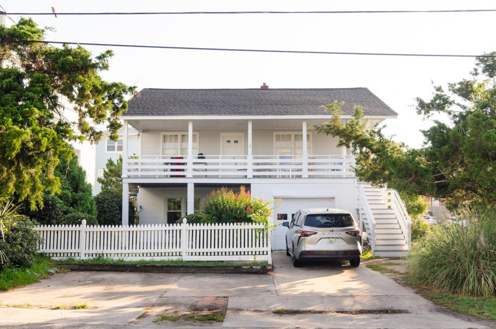 a white house with a white fence and a car at Craft Upper Unit by Bryant Real Estate in Wrightsville Beach