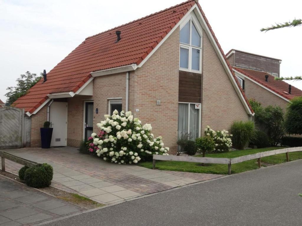 ein Backsteinhaus mit weißen Blumen davor in der Unterkunft Bungalow in Breskens near the Lighthouse in Breskens