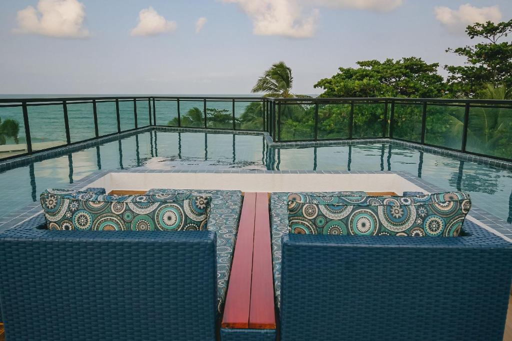 a view of a swimming pool with two chairs and the ocean at Aconchego, varandinha e vista mar em Maracaípe in Porto De Galinhas