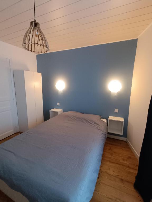 - une chambre dotée d'un mur bleu avec un lit et deux lumières dans l'établissement Studette pour 1 ou 2 personnes, à Chaumont