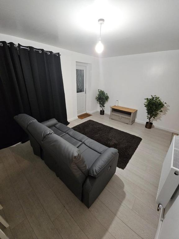 a living room with a leather couch and black curtains at Spacious single room in Nottingham