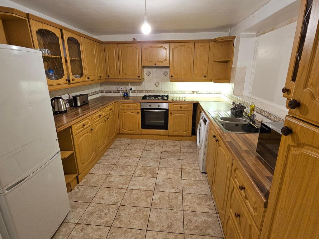 a kitchen with wooden cabinets and a white refrigerator at Spacious single room in Nottingham