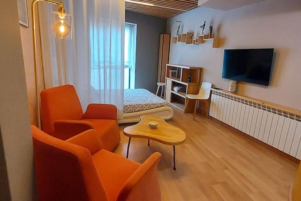 ein Wohnzimmer mit orangefarbenen Stühlen und einem Fernseher in der Unterkunft Estudio de diseño con parking en el centro in Huesca
