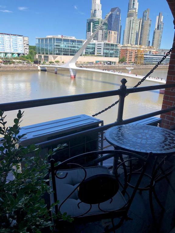 a table and a bench on a balcony overlooking a river at Puente de la Mujer in Buenos Aires