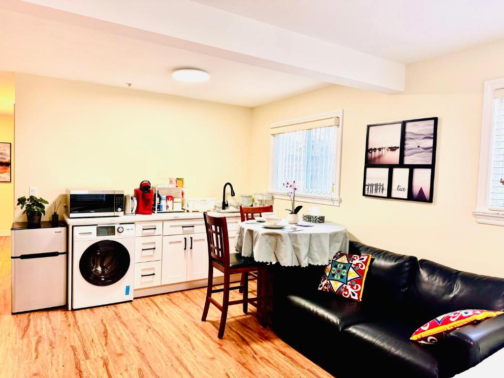 a living room with a table and a kitchen at 13 Mins to Downtown-Free Parking near Joyce Skytrain -2 Beds in Vancouver