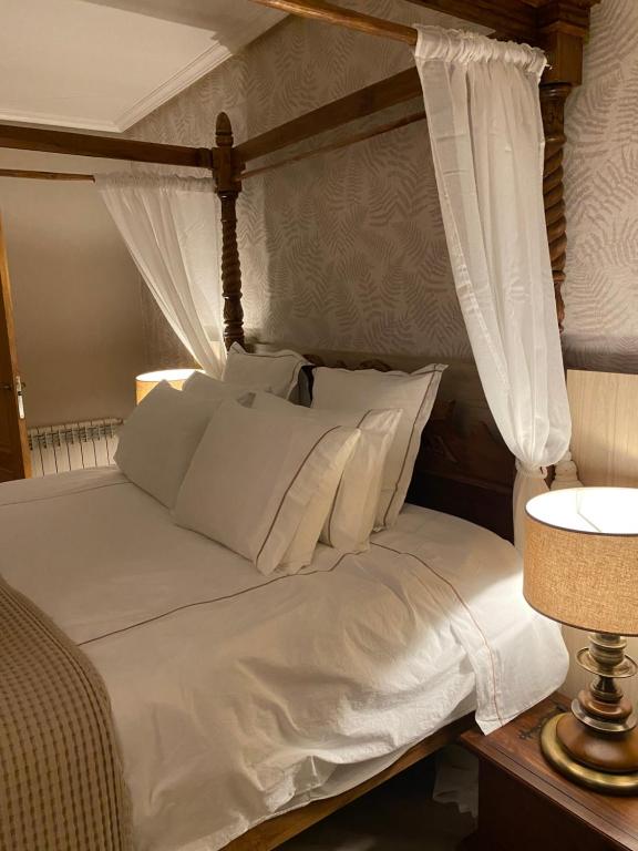 uma cama de dossel branca com almofadas brancas em Hotel Lusitano em Vilar Formoso