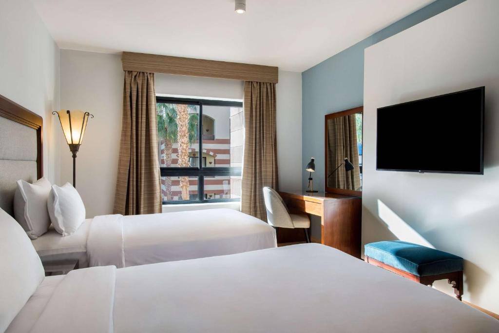 a hotel room with two beds and a flat screen tv at Marina Resort Port Ghalib, a member of Radisson Individuals in Port Ghalib