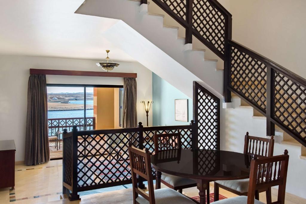 a dining room with a table and chairs and a staircase at Marina Resort Port Ghalib, a member of Radisson Individuals in Port Ghalib