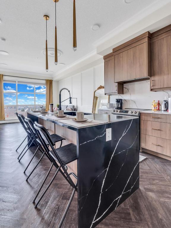 a kitchen with a large black island with chairs at Elegant Downtown Condo with Balcony & Parking in Calgary