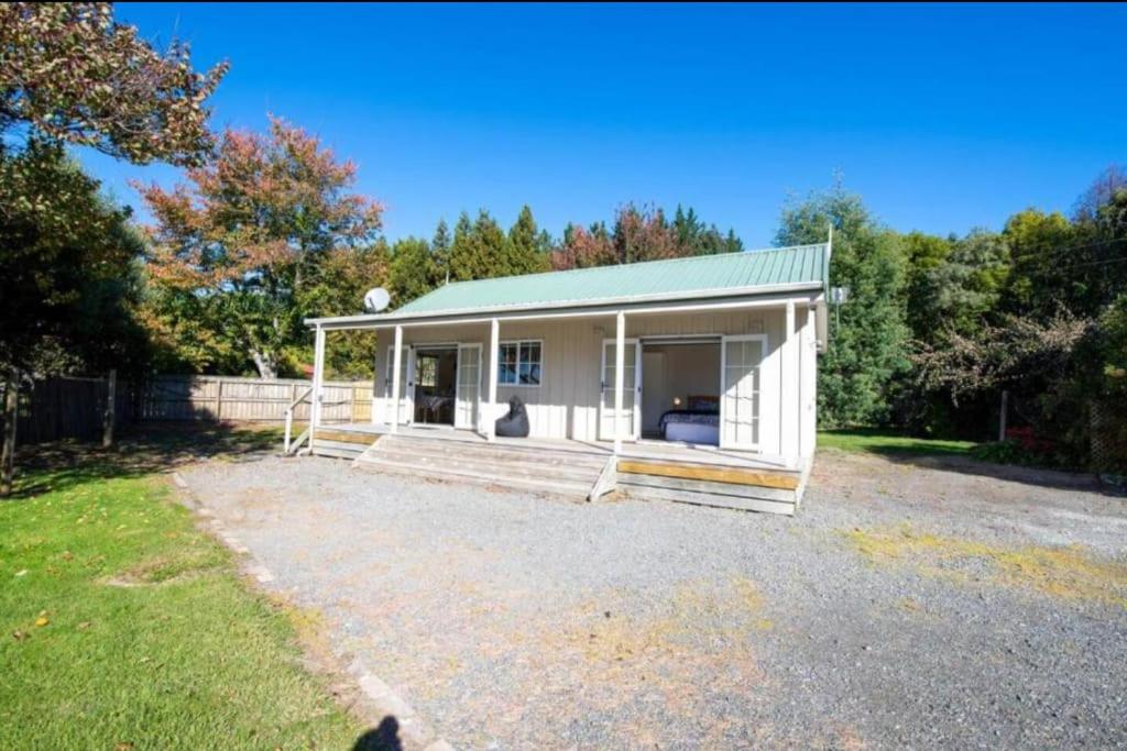 a small white house with a porch and a yard at Grace Cottage in Turangi