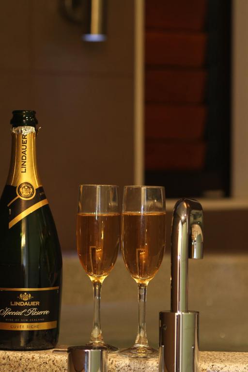 two glasses of wine next to a bottle of champagne at Bentleys Motor Inn in Palmerston North