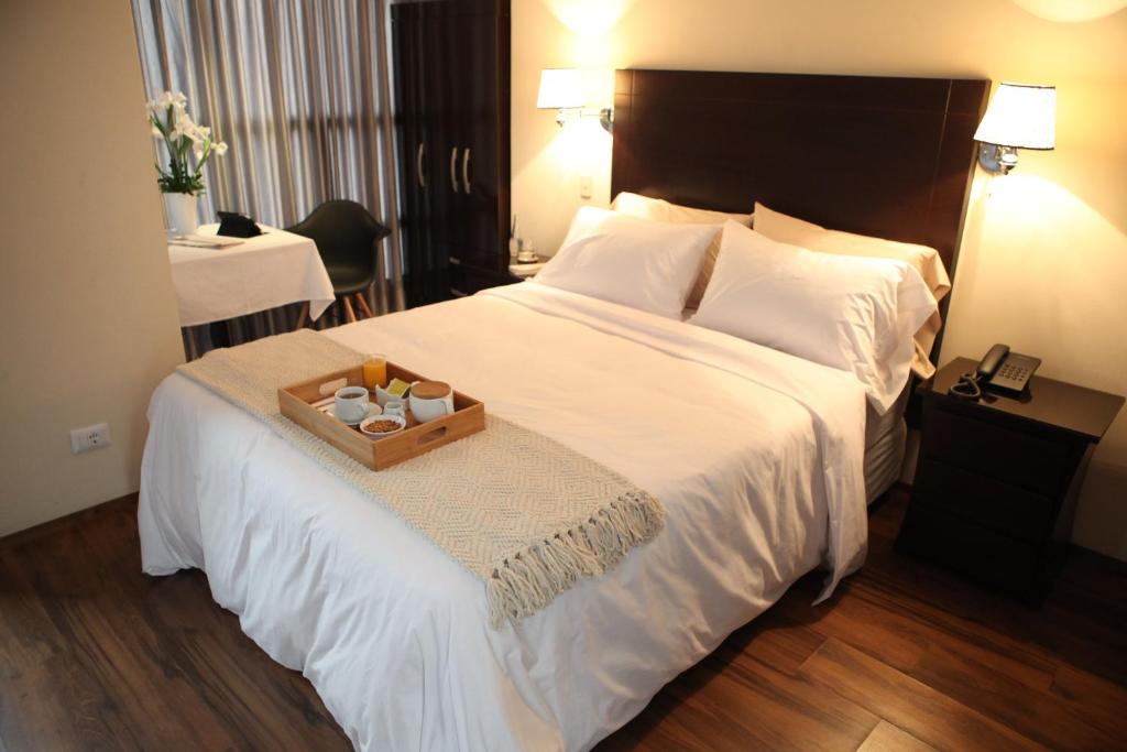 una camera d'albergo con un grande letto e un vassoio di Park Hotel Lima a Lima