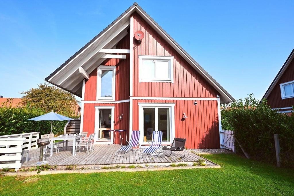 a red house with a deck with a table and chairs at Sechendorf-Ferienhaus-Solhem-Sechendorf in Blekendorf