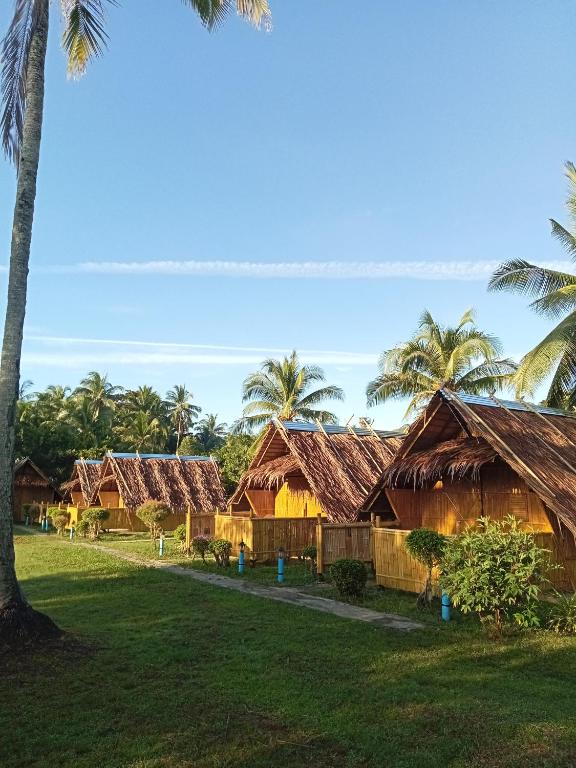a group of houses with palm trees in the background at koh mook oyoy reggaebar bungalow in Ko Mook