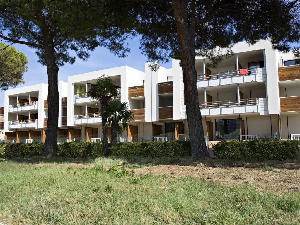 un immeuble d'appartements avec des arbres devant dans l'établissement Charming Apt in Mandelieu, à Mandelieu-la-Napoule