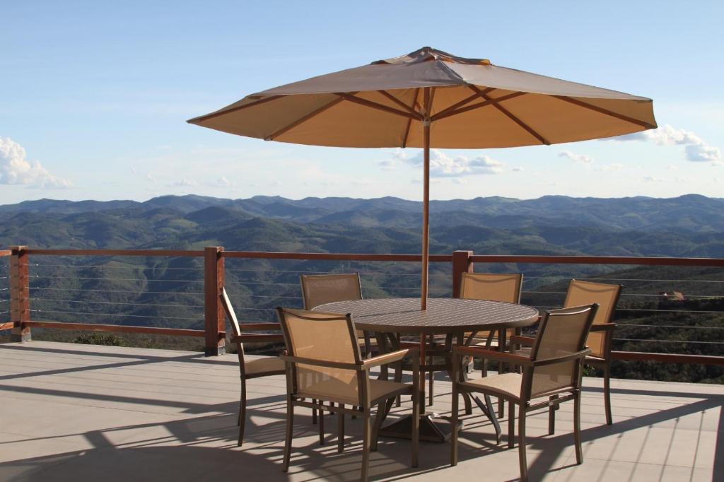 a table and chairs with an umbrella on a deck at Casa Tramonto in Lavras Novas