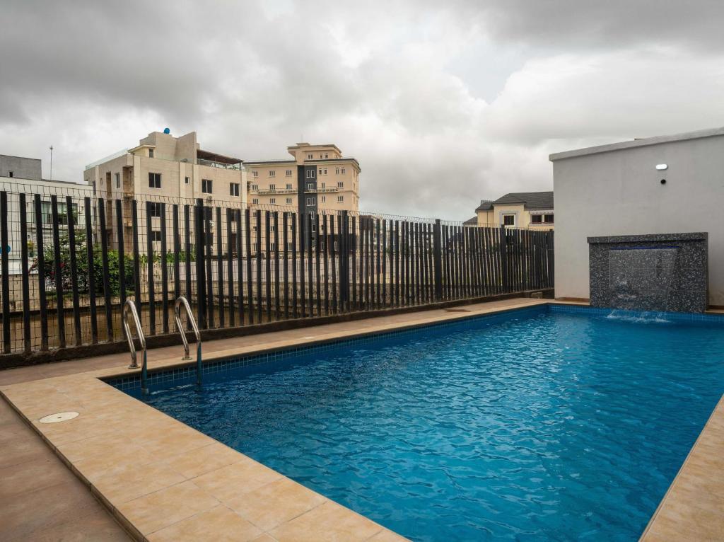 a large blue swimming pool in front of a fence at George Residence Banana Island Road, Ikoyi in Lagos