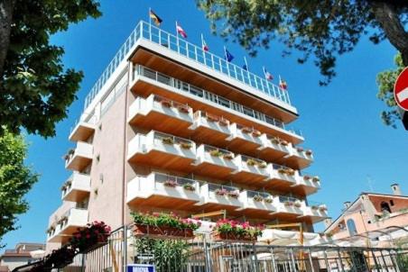 un alto edificio con balconi e fiori di Hotel Villa Doimo a Lignano Sabbiadoro