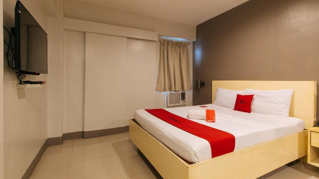 a hotel room with a bed with a red pillow at RedDoorz at Samat Mandaluyong in Manila