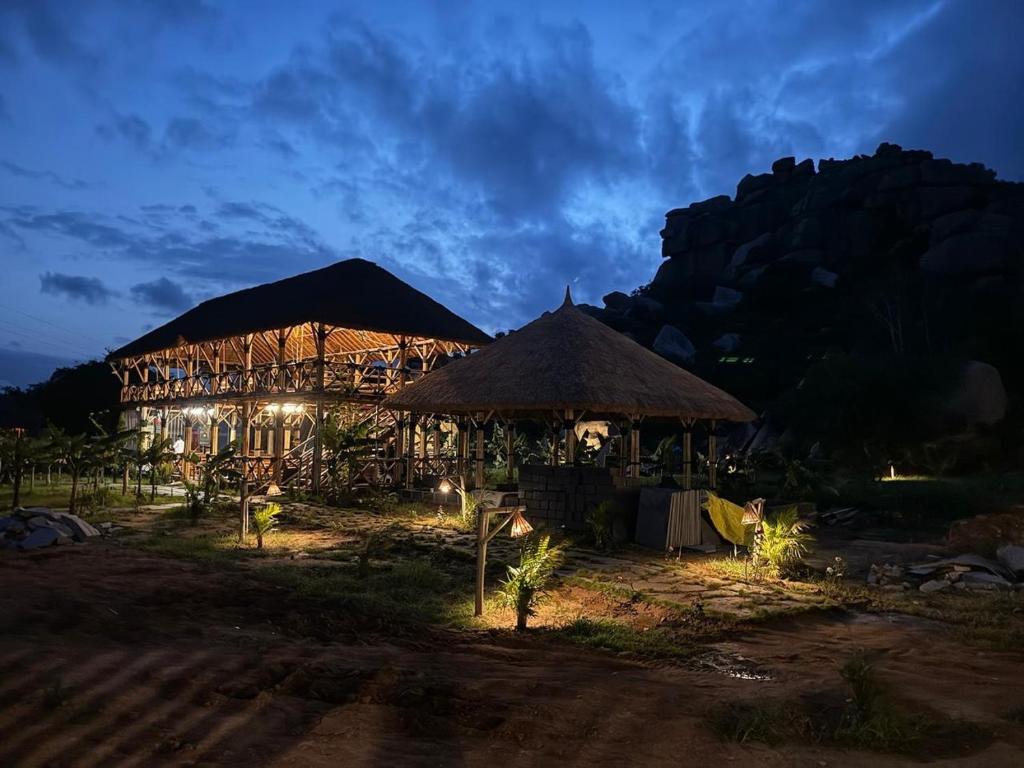 a resort with two thatched umbrellas at night at Hill Stone View Hampi in Hampi