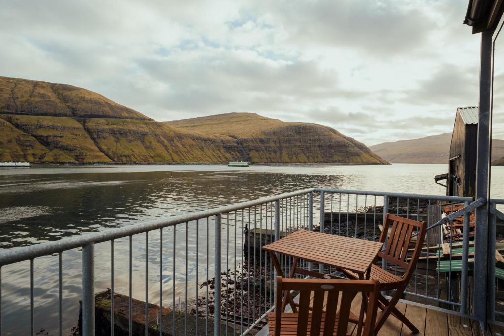 VestmannaにあるCharming Boathouse with Panoramic Fjord Viewsの水を見渡すバルコニー(テーブル、椅子付)