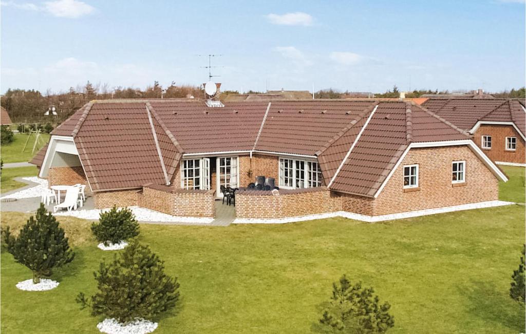 a house with a brown roof on a green yard at Awesome Home In Blåvand With Sauna in Blåvand
