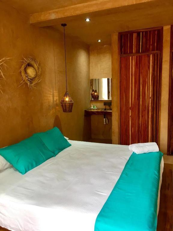 a bedroom with a large white bed with blue pillows at Hotel Rinconcito de Mazunte in Santa María Tonameca