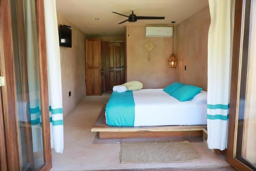 ein Schlafzimmer mit einem Bett mit blauen Kissen in der Unterkunft Hotel Rinconcito de Mazunte in Santa María Tonameca