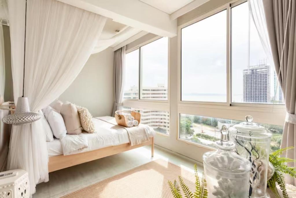 a bedroom with a bed and a large window at Family Sea view 2Bedroom พร้อมครัว ติดทะเล at Veranda Pattaya in Na Jomtien